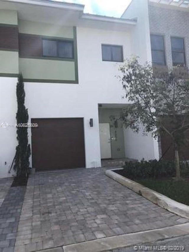 view of front of house featuring an attached garage, decorative driveway, and stucco siding