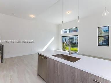 kitchen with dishwasher, modern cabinets, light countertops, and a sink