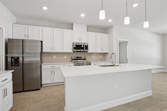 kitchen with a sink, stainless steel appliances, light countertops, white cabinets, and backsplash