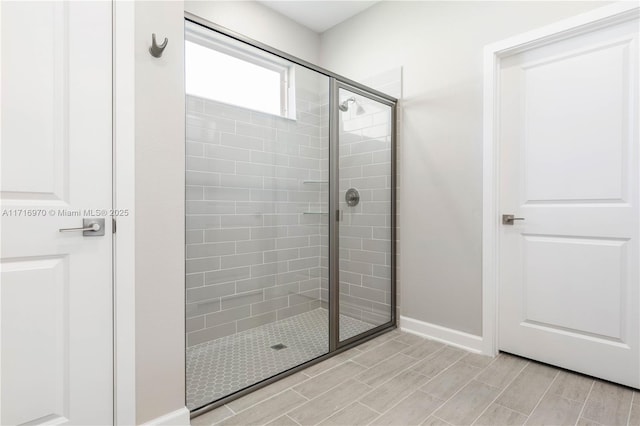 full bath featuring baseboards, a tile shower, and wood tiled floor