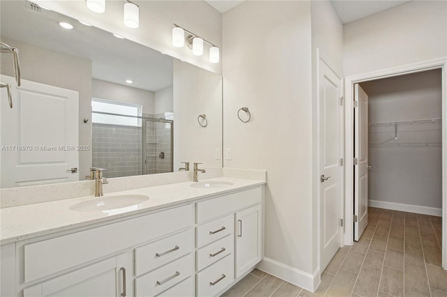 full bathroom with a shower stall, double vanity, baseboards, and a sink