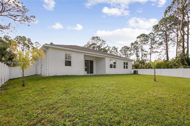 rear view of property with stucco siding, central air condition unit, a lawn, and a fenced backyard