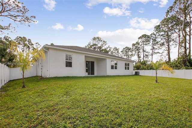 back of house featuring central AC unit, a yard, a fenced backyard, and stucco siding