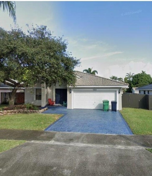 view of front of property with a front lawn, driveway, an attached garage, and fence