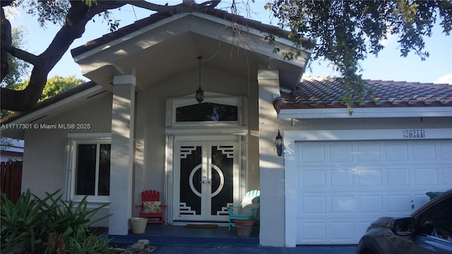 property entrance featuring a tiled roof, an attached garage, and stucco siding