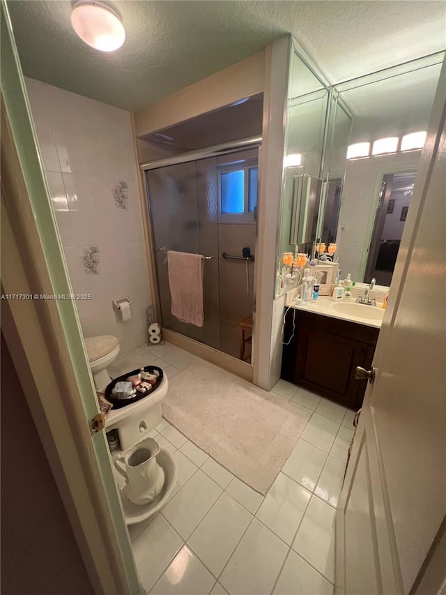 bathroom featuring toilet, a shower stall, a textured ceiling, vanity, and tile patterned flooring