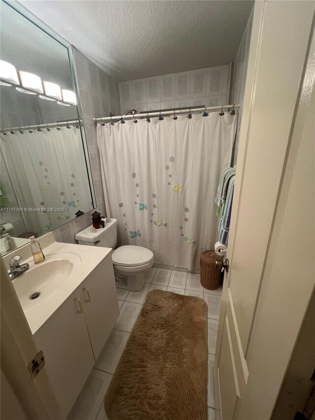 bathroom with vanity, a textured ceiling, curtained shower, tile patterned floors, and toilet