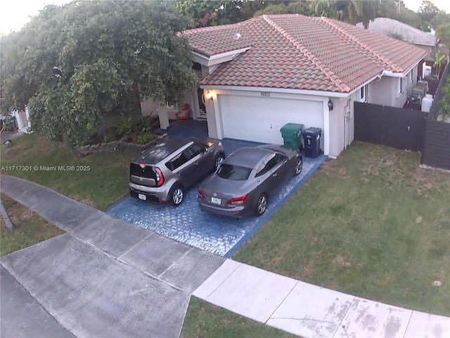 view of front facade with a garage, a tiled roof, driveway, stucco siding, and a front lawn