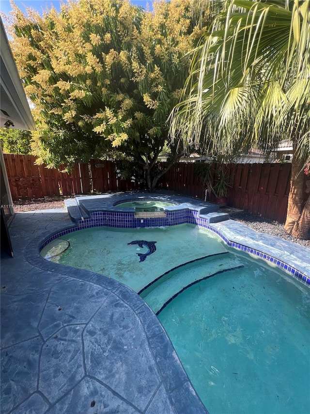 view of pool with a pool with connected hot tub and a fenced backyard