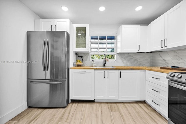 kitchen with sink, white cabinets, stainless steel appliances, and wood counters