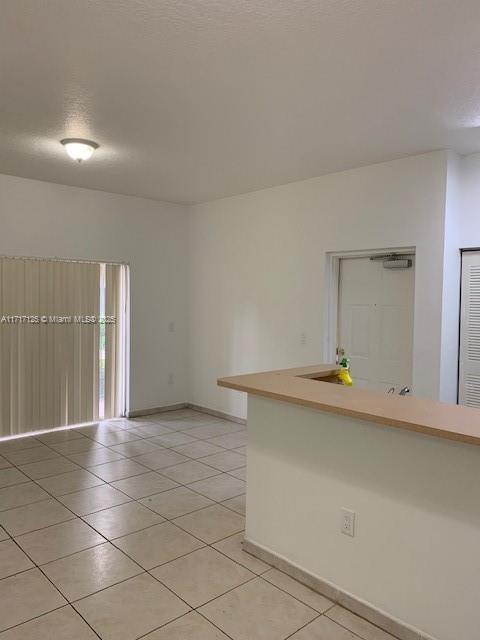 unfurnished room with light tile patterned flooring and a textured ceiling