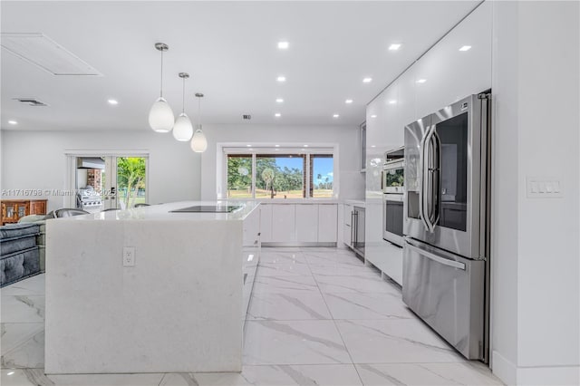 kitchen featuring decorative light fixtures, stainless steel appliances, and white cabinetry