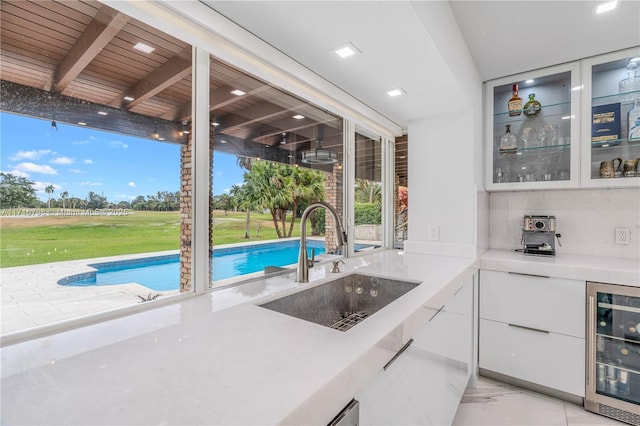 kitchen featuring wood ceiling, white cabinetry, sink, and wine cooler