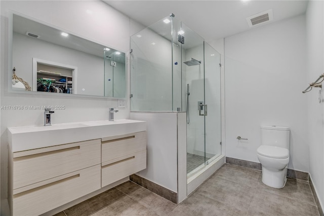 bathroom with a shower with door, vanity, and toilet