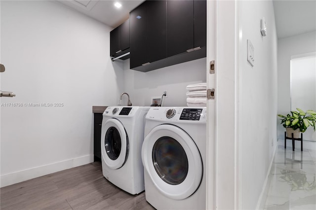 washroom with separate washer and dryer, cabinets, and wood-type flooring