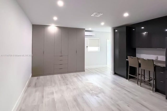 interior space featuring an AC wall unit, a breakfast bar area, and light hardwood / wood-style flooring