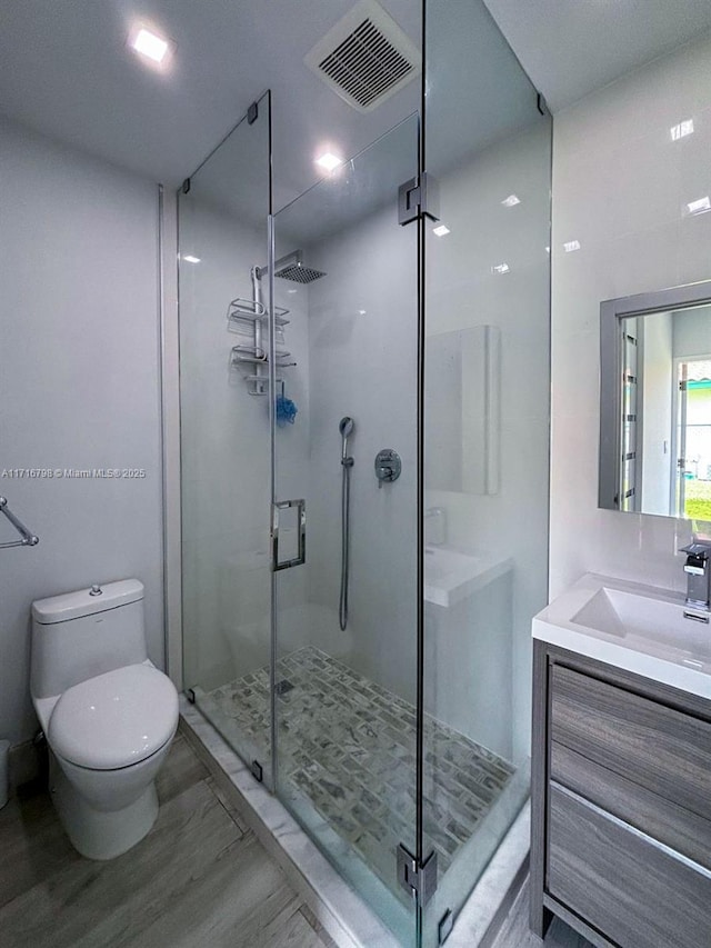 bathroom with vanity, hardwood / wood-style flooring, toilet, and a shower with shower door