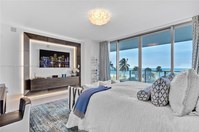 bedroom featuring a water view, access to exterior, and expansive windows