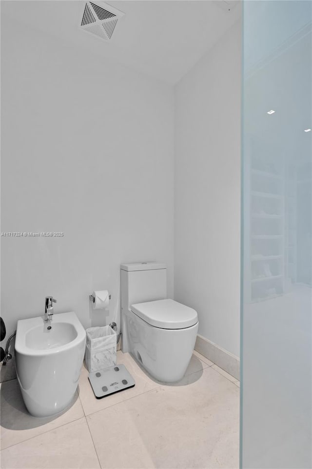 bathroom featuring tile patterned flooring, toilet, and a bidet