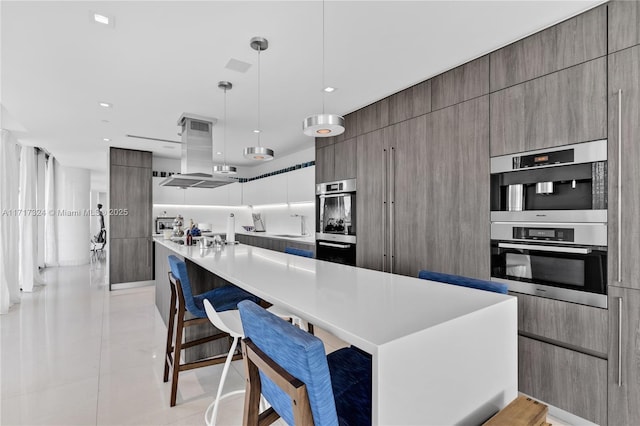 kitchen with hanging light fixtures, island exhaust hood, a spacious island, a kitchen bar, and light tile patterned floors