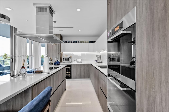 kitchen featuring white cabinets, decorative backsplash, light tile patterned floors, cooktop, and island exhaust hood