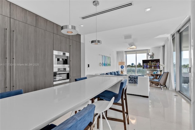 kitchen with pendant lighting, double wall oven, a breakfast bar area, and light tile patterned flooring