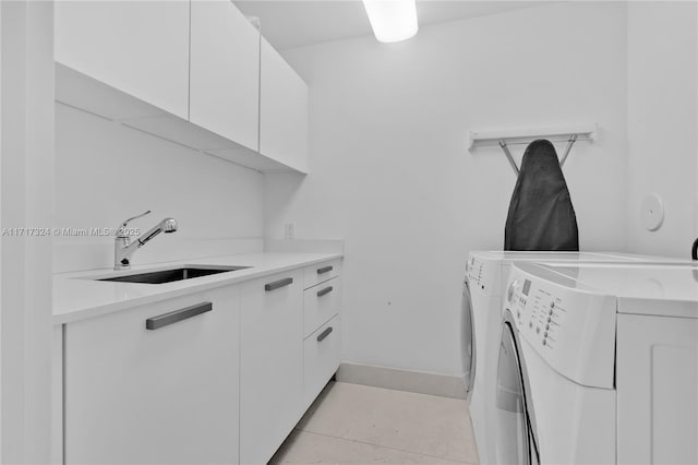 laundry area featuring cabinets, light tile patterned floors, washing machine and dryer, and sink