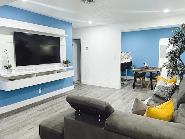 living room with a textured ceiling and light wood-type flooring