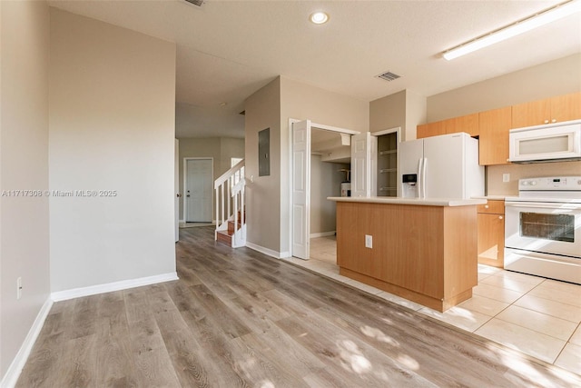 kitchen with a kitchen island, white appliances, light brown cabinets, and light hardwood / wood-style flooring