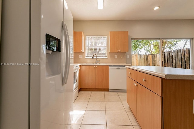 kitchen with light tile patterned flooring, white appliances, plenty of natural light, and sink