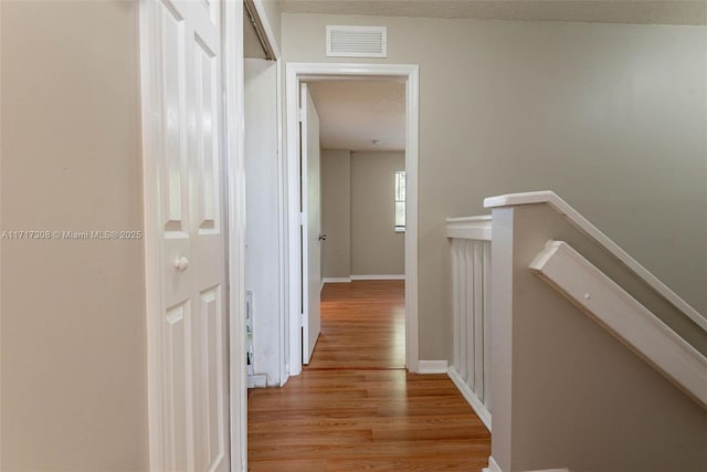 hallway with a textured ceiling and light hardwood / wood-style flooring