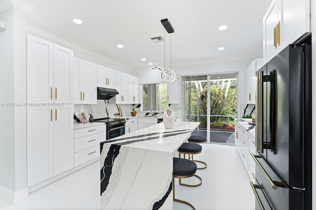 kitchen featuring sink, hanging light fixtures, light stone countertops, appliances with stainless steel finishes, and white cabinetry