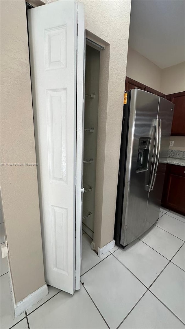 kitchen featuring dark brown cabinets, stainless steel fridge, and light tile patterned floors