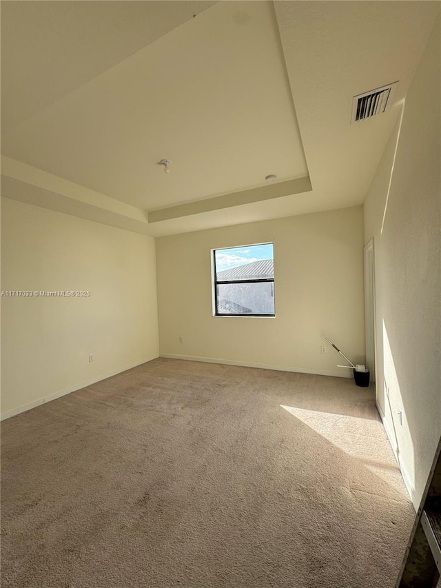 carpeted empty room with a raised ceiling