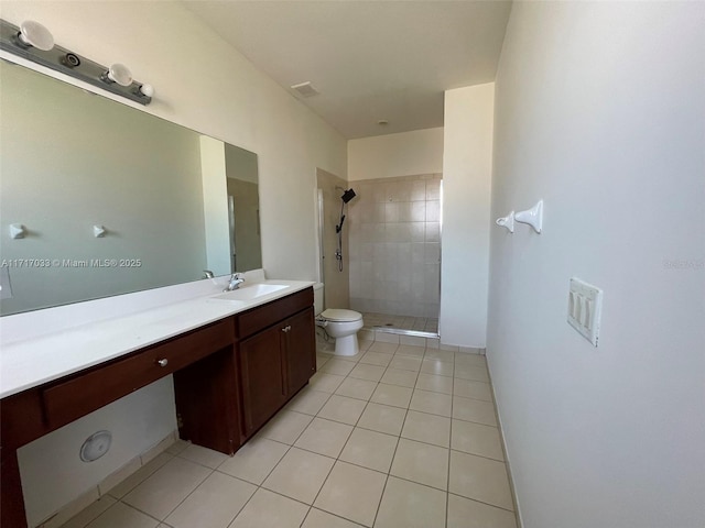 bathroom featuring tile patterned flooring, vanity, toilet, and tiled shower