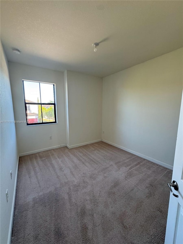 spare room featuring carpet floors and a textured ceiling