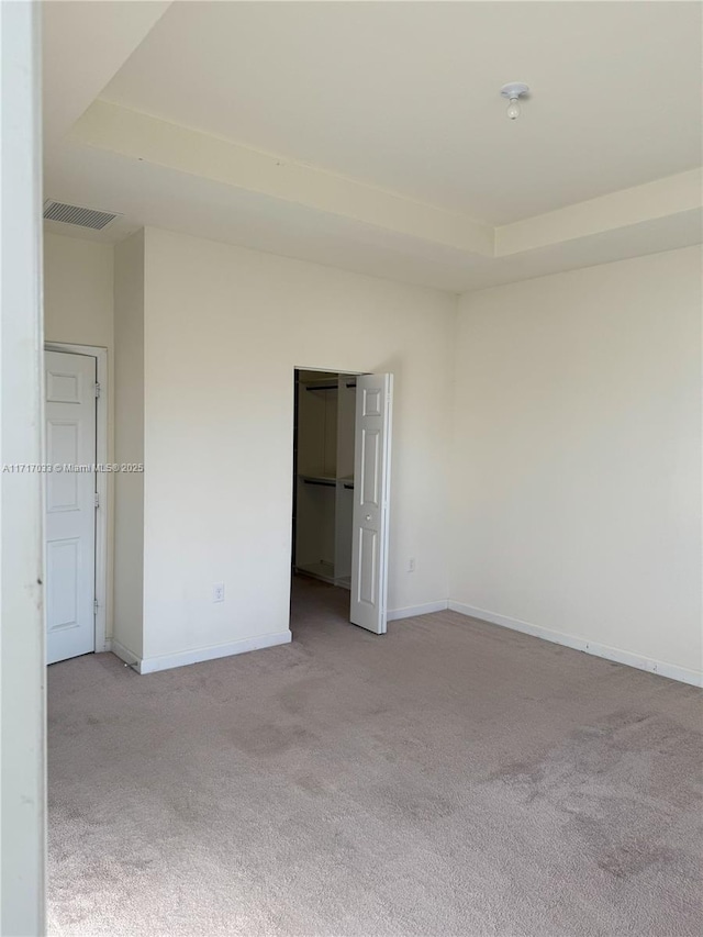 unfurnished room with light carpet and a tray ceiling