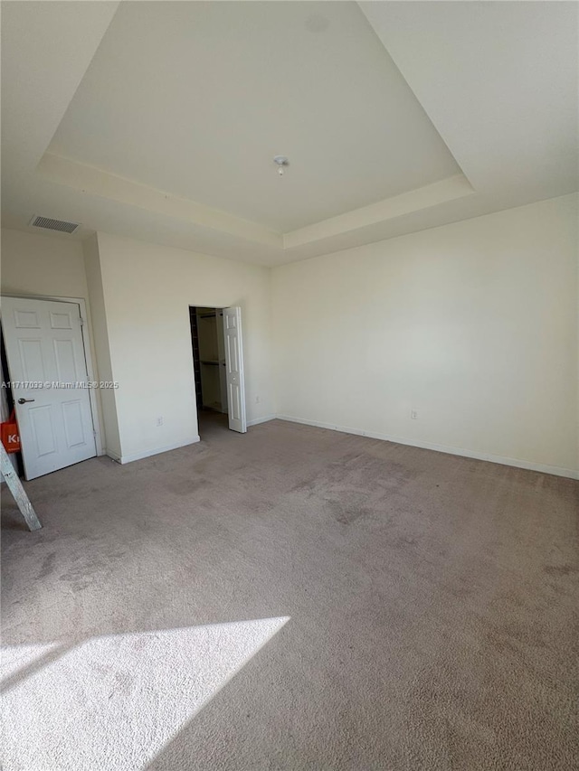 unfurnished bedroom featuring carpet and a raised ceiling