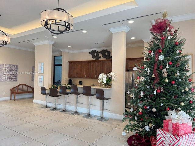 kitchen with an inviting chandelier, a kitchen breakfast bar, kitchen peninsula, light tile patterned floors, and ornamental molding