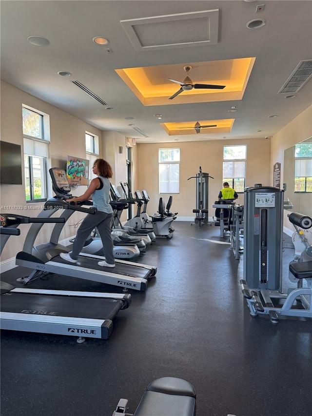 workout area with ceiling fan and a raised ceiling