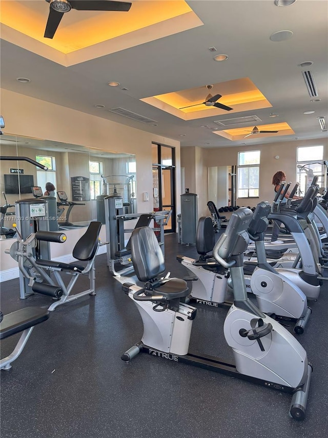 gym featuring a raised ceiling and ceiling fan