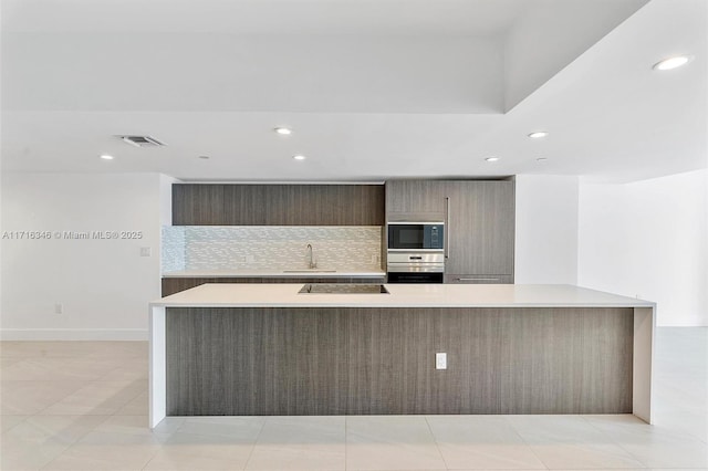 kitchen featuring tasteful backsplash, sink, light tile patterned floors, and black appliances