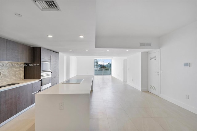 kitchen featuring built in microwave, sink, a center island, wall oven, and decorative backsplash