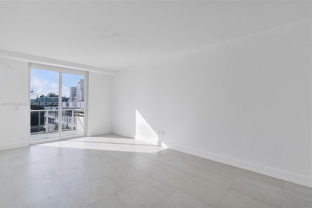 empty room featuring floor to ceiling windows and light tile patterned floors