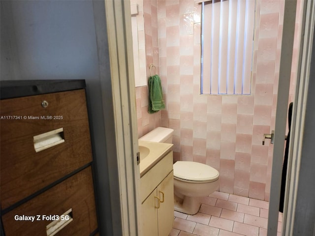 bathroom featuring vanity, toilet, tile patterned flooring, and tile walls