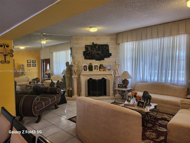 tiled living room featuring a healthy amount of sunlight, a large fireplace, and a textured ceiling