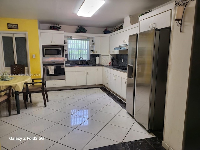 kitchen with sink, appliances with stainless steel finishes, tasteful backsplash, white cabinets, and light tile patterned flooring