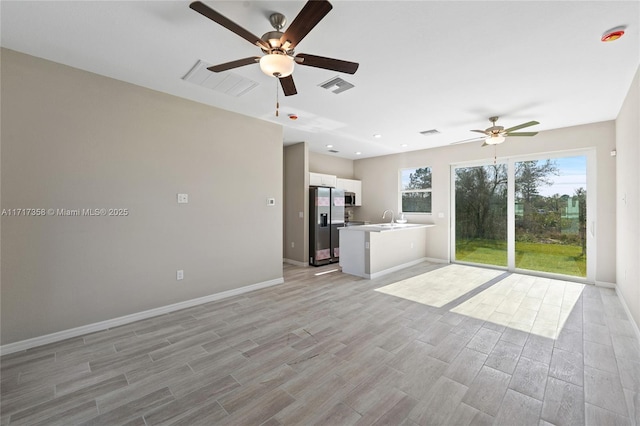 unfurnished living room with ceiling fan, sink, and light hardwood / wood-style floors