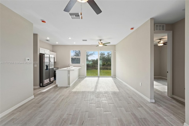 kitchen featuring white cabinetry, sink, light hardwood / wood-style floors, kitchen peninsula, and stainless steel appliances