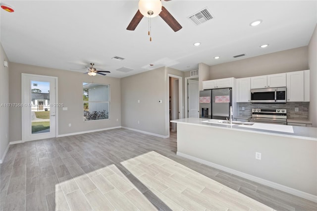 kitchen with sink, white cabinetry, stainless steel appliances, decorative backsplash, and light wood-type flooring